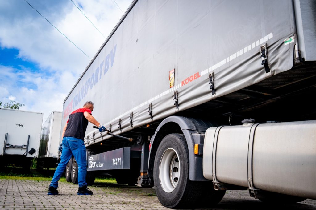 Chauffeur zekert de lading onder de huifoplegger van Voets Transport