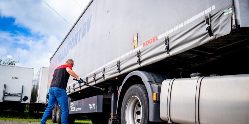 Chauffeur zekert de lading onder de huifoplegger van Voets Transport